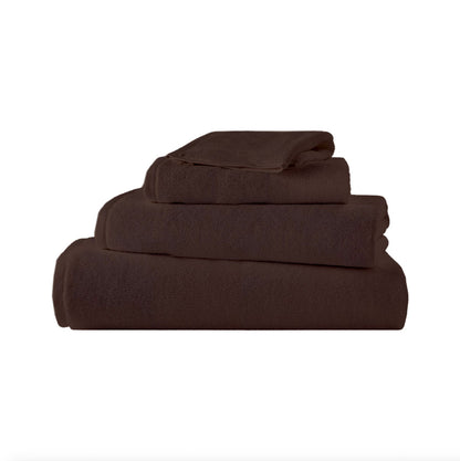 Serviette Brodo en coton moelleux soigneusement pliée sur une étagère de salle de bain élégante.
