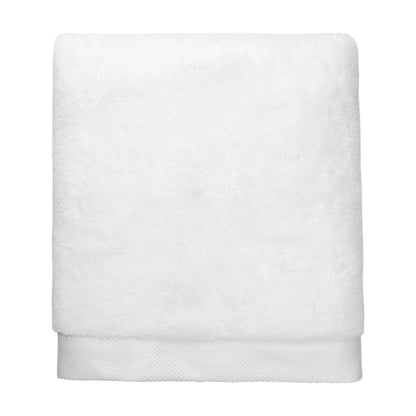Serviette Brodo en coton moelleux soigneusement pliée sur une étagère de salle de bain élégante.
